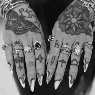 tattooed hands with multiple diamond and gemstone rings