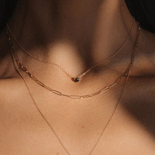 close up of woman's décolletage wearing a black diamond stud necklace and other chains