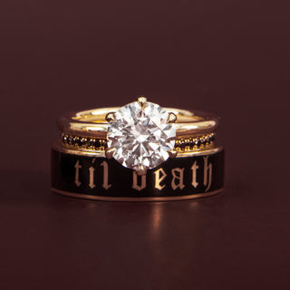 stack of round diamond solitaire with a til death black enamel band against a reddish-brown background
