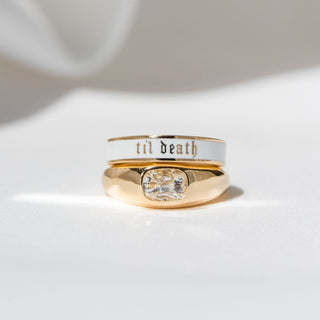 flat lay of diamond bombe ring with white til death band on top against a white background