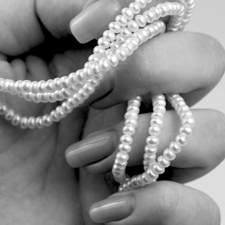 hand holding strings of pearls in black and white