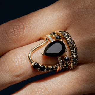 close up of hand with multiple black onyx & black diamond rings stacked together