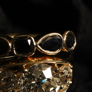 Black Diamond Mixed Shape Bezel Band stacked with an oval diamond ring on dark textured fabric