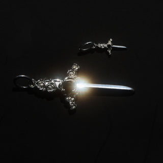 two silver dagger charms on a black background