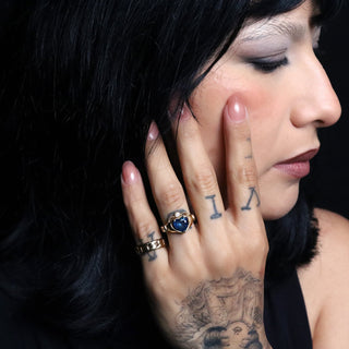 Woman with black hair and tattoos wearing the 2.82ct Sapphire Sempre Ring against a black background
