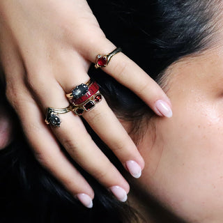 Woman's hand wearing the 6mm cherry mocha Til Death band with red and black stone rings, dark background