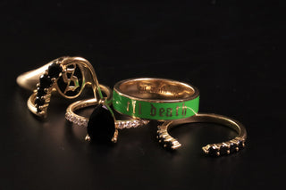 Three gold rings with green text and black gemstones on a black background