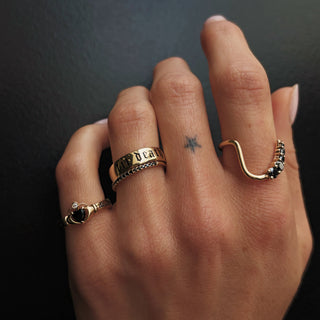 Ring stack with the 4mm Onyx Sempre Ring, Til Death Gold Band, Black Diamond Whisper band and Black Diamond Lucy Wave Band on a dark background