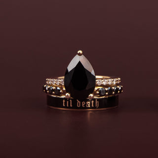 Three rings with a teardrop-shaped black gemstone on a dark brown background