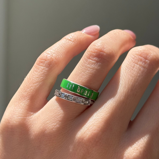 Hand wearing green enamel band that says "til death" and diamond stacking band