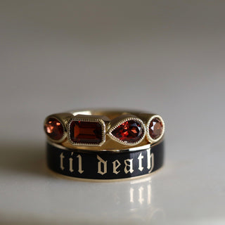 Ring with gemstones and 'til death' engraving on a gray background