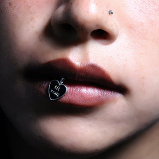 Sterling silver Til Death enamel heart charm held to the lip, Old English lettering on black enamel