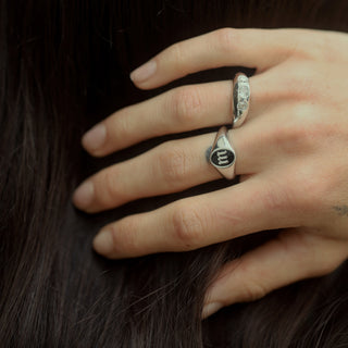 Hand wearing the sterling silver Initial Enamel Signet Ring with the letter M and a white diamond bombe ring