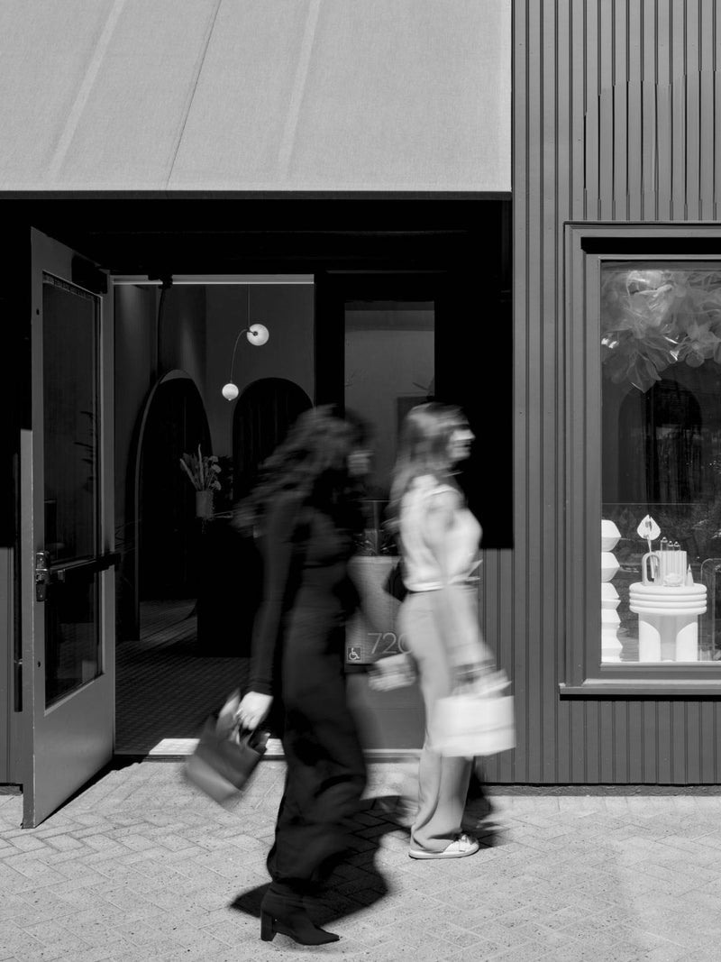 Two women walking out of a building with a blurred effect in black and white