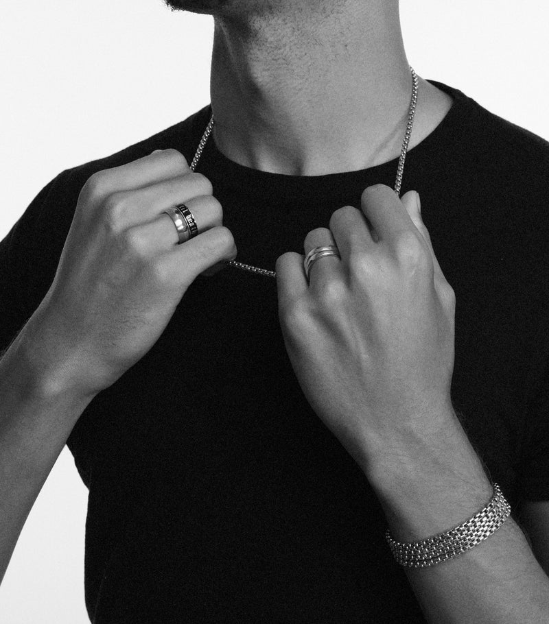 Person wearing a necklace with visible jewelry on a plain background