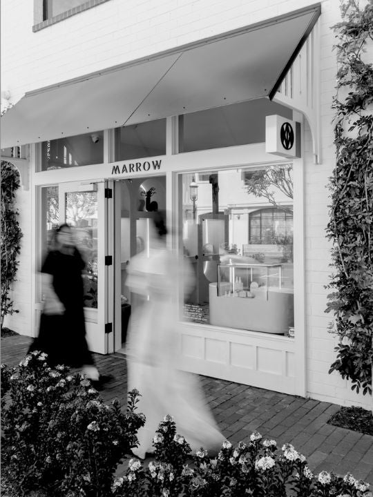 Storefront with 'Marrow' sign, people walking by, and flowers in foreground