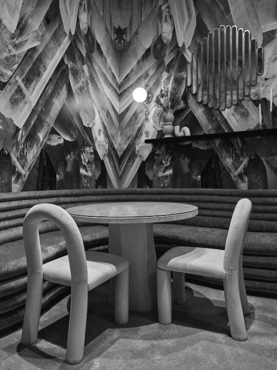 Modern area with round table and chairs against a decorative wall.