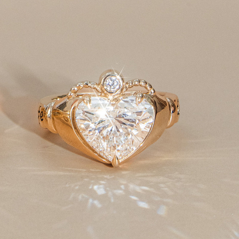 Gold ring with a heart-shaped diamond on a beige background