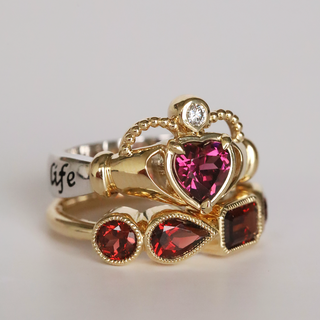 Gold ring with heart-shaped gemstones on a light gray background