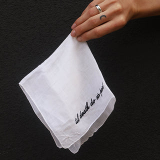 White handkerchief with text held by a hand against a black background