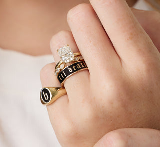 Hand wearing three gold rings with a diamond on a neutral background