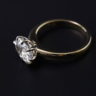 Ophelia solitaire with an east-west oval lab-created diamond in a claw-prong yellow gold setting, on a black background