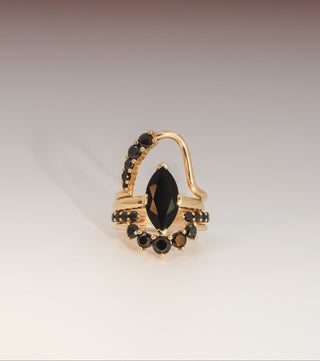 Gold ring with black gemstones on a gradient background
