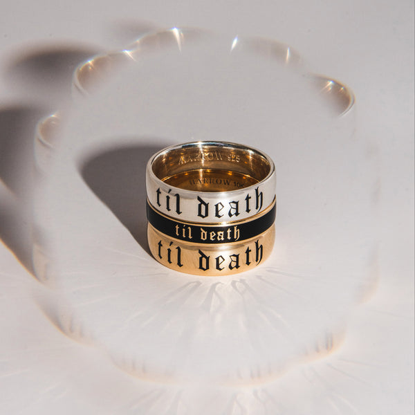 Two gold rings with 'till death' engraving on a white surface