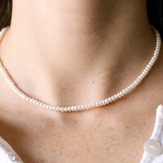 Pearl necklace worn by a person with a white top