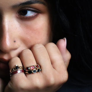 Person resting their chin on their hands, wearing the Black Diamond and Garnet Mixed Shape bands on a dark background