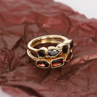 Stack of gold rings with gemstones on crumpled brown paper