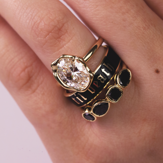 Gold ring with a large diamond on a person's finger against a neutral background