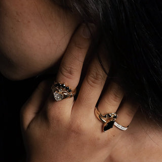 Hand wearing the Black Diamond Crescendo Stacking Band, Curvy Black Diamond Headdress Jacket, a lab-created diamond Sempre ring and a white enamel Til Death band