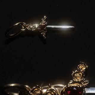 small and large gold dagger charms on black background