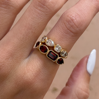 Close-up of a hand wearing a ring with gemstones on a neutral background