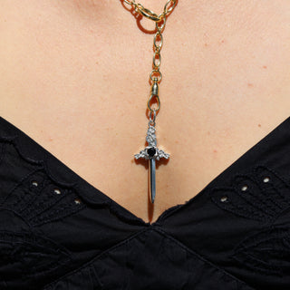 Necklace with a sword-shaped pendant on a person wearing a black top.