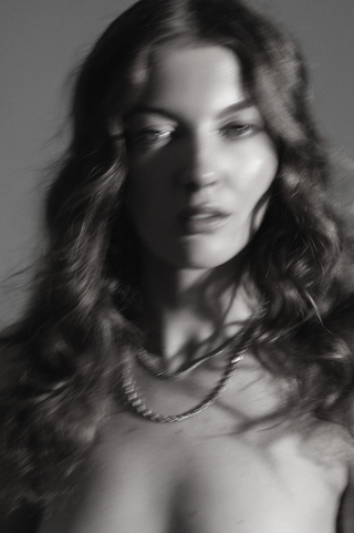 Black and white portrait of a woman with wavy hair and a necklace.