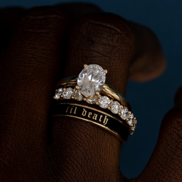 Gold ring with a large diamond and smaller diamonds on a dark background