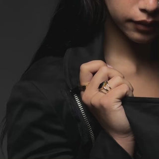 Video of model with black rings on hand, holding collar of black jacket and moving her hand to show the rings.