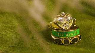 Gold ring with a heart-shaped gemstone on a green background