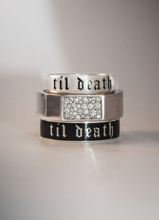 Three silver rings with 'til death' engraving on a gray background
