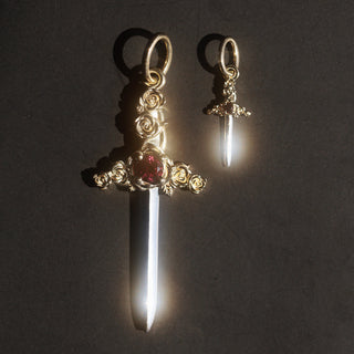 Gold pendant with a red garnet on a dark background