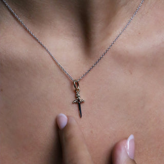 Small gold Cross My Heart dagger charm worn on a chain