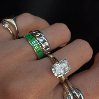 Close-up of a hand wearing multiple rings with a focus on a gold ring with a diamond.