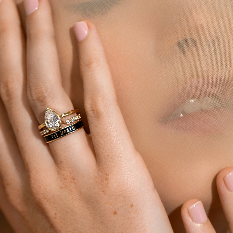 Hand wearing a gold ring with a diamond on a sheer fabric background