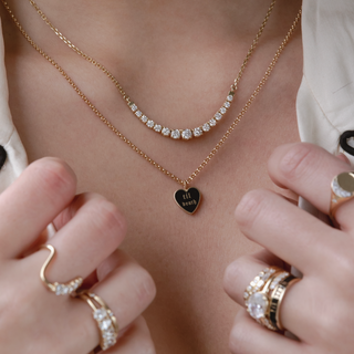 Close-up of a person wearing multiple gold necklaces and rings on a neutral background